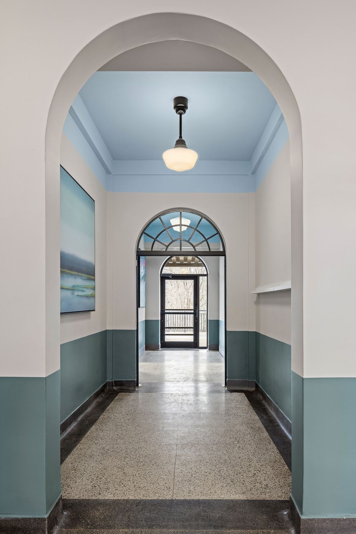 Arched hallway with a fanlight door at the far end, two-tone teal walls