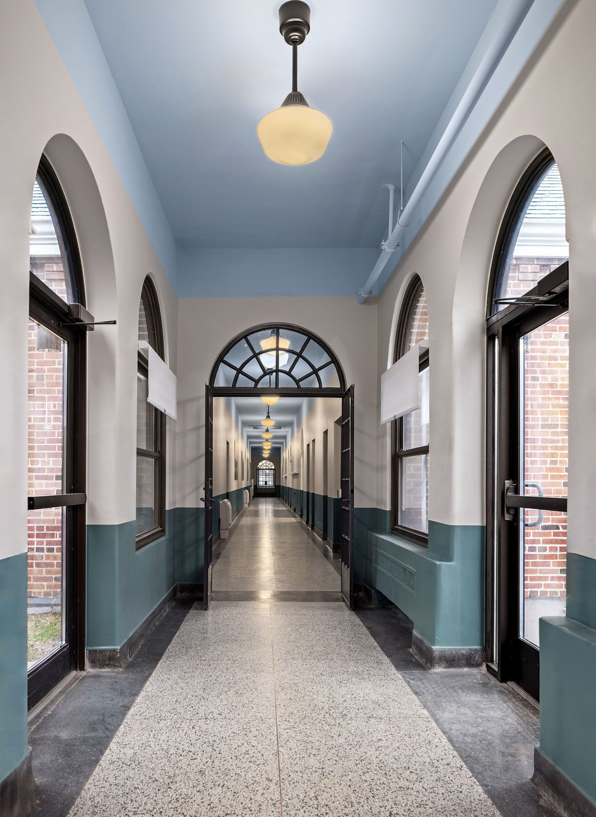 Long arched corridor with terrazzo floor and teal wainscot, Appalachian Center for Hope