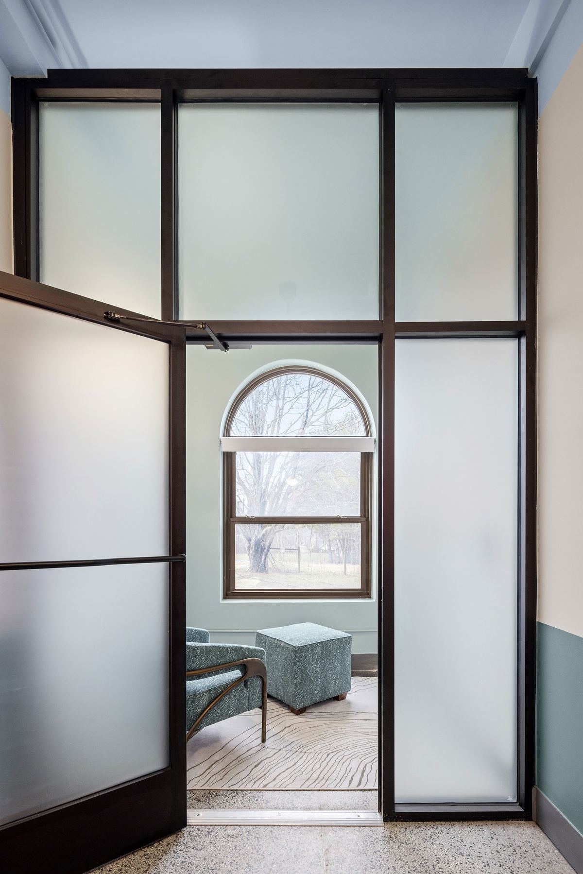 Steel and frosted glass doorway framing an arched window