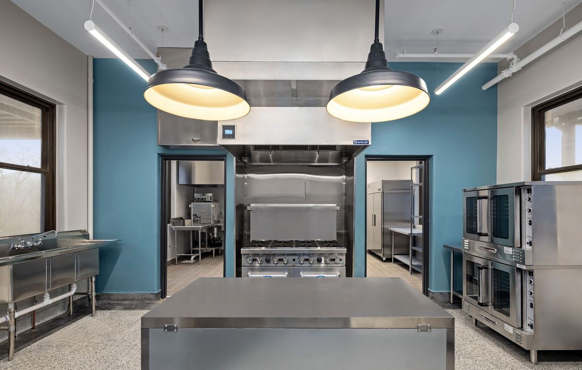 Teaching kitchen under black pendant lights, teal walls