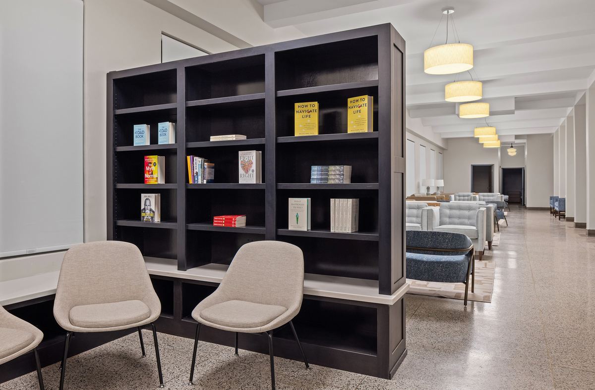 Bookshelves and lounge chairs at the head of a long common room