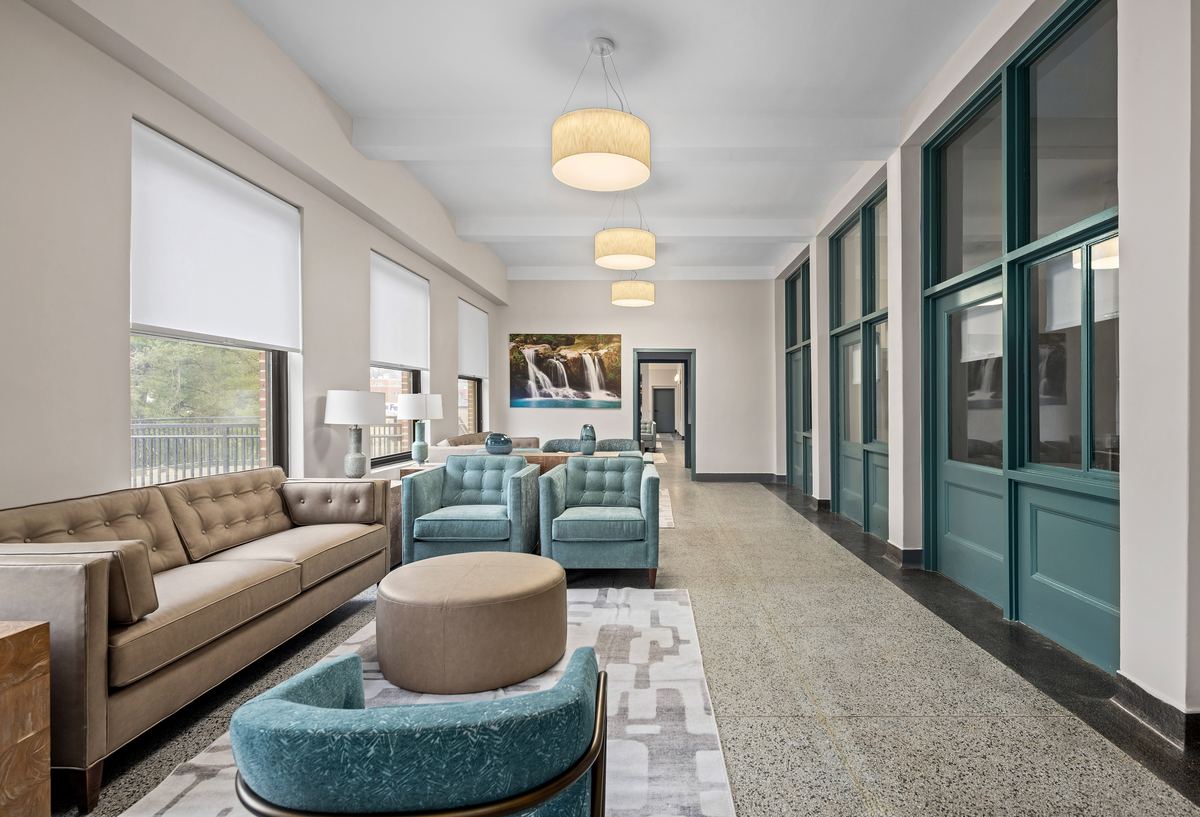 Renovated lounge with teal armchairs and a wall of steel windows