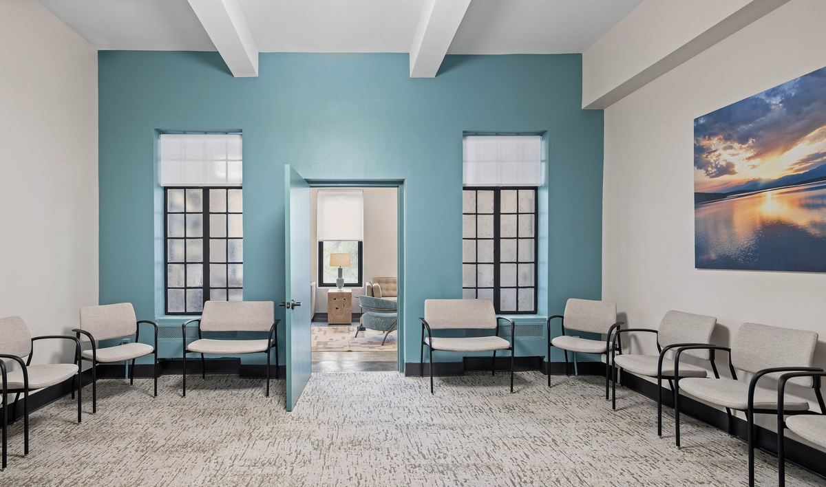 Waiting room with a teal feature wall and steel-framed windows