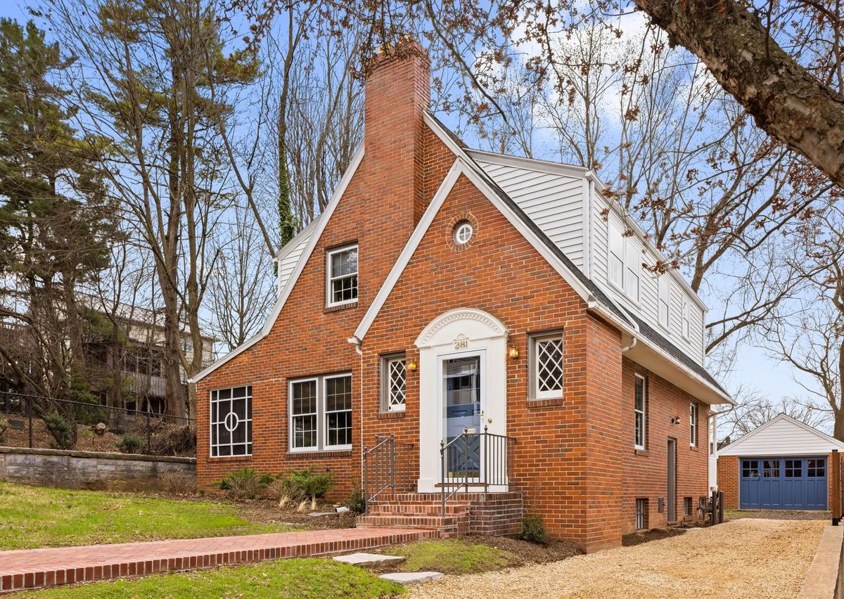 Brick cottage with an arched white entry and a tall chimney, early spring