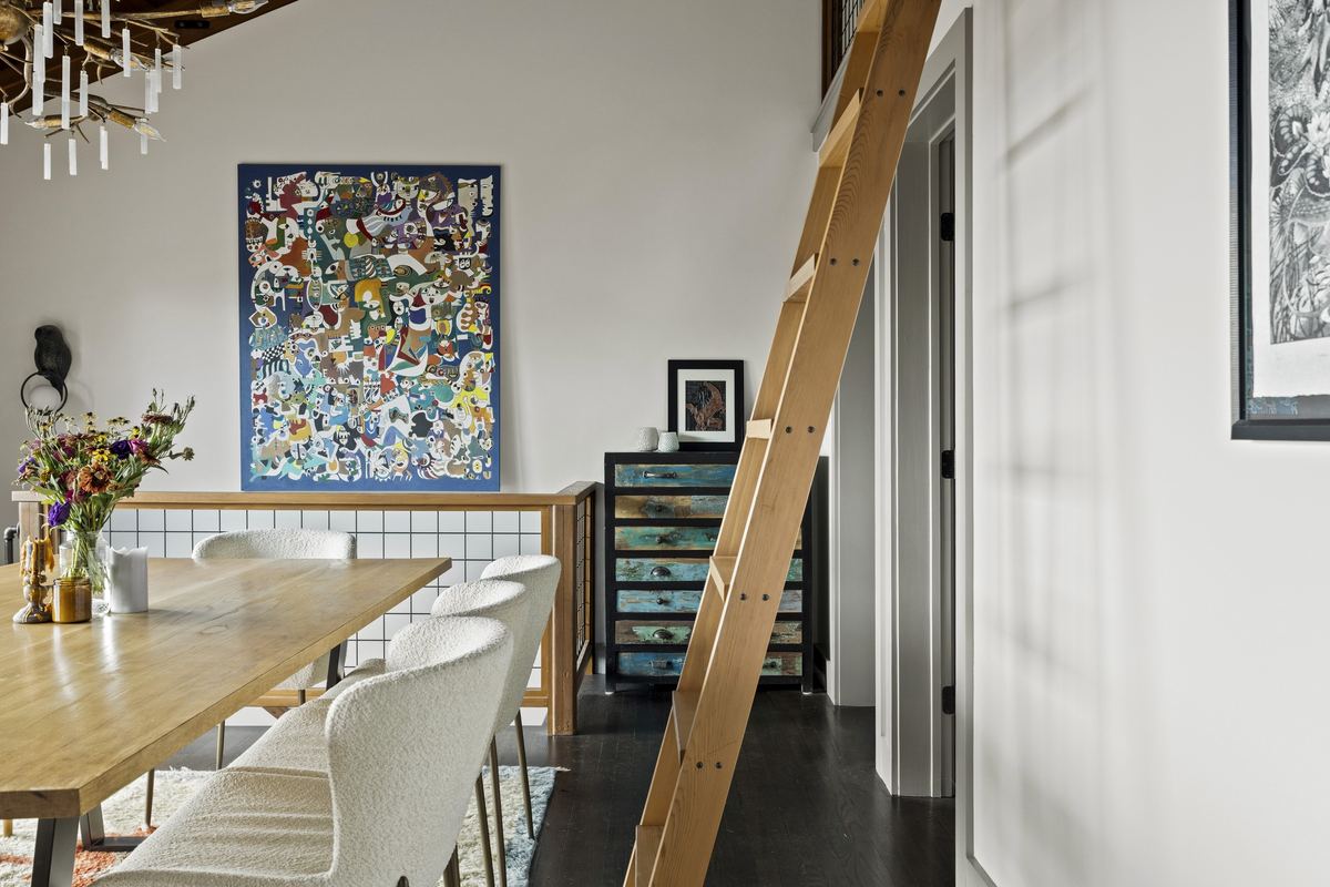 Dining room under a timber ceiling, a library ladder and a large abstract canvas