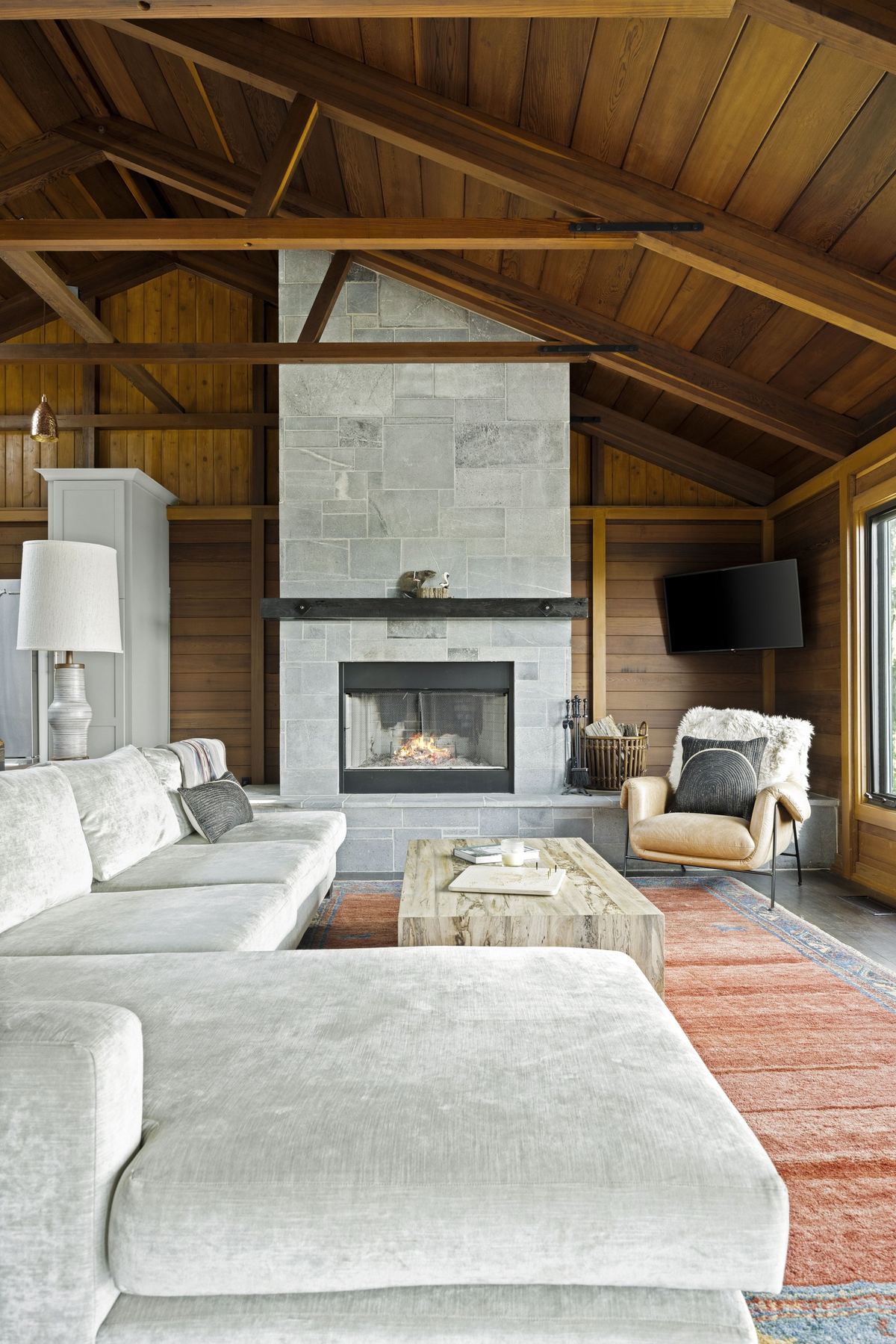 Great room with a tiled fireplace under vaulted cedar