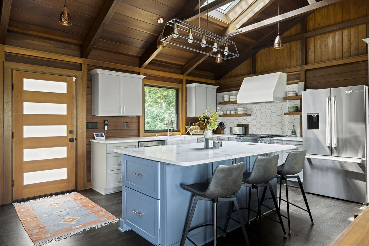 Kitchen with a blue island and a glass-panelled door under timber beams