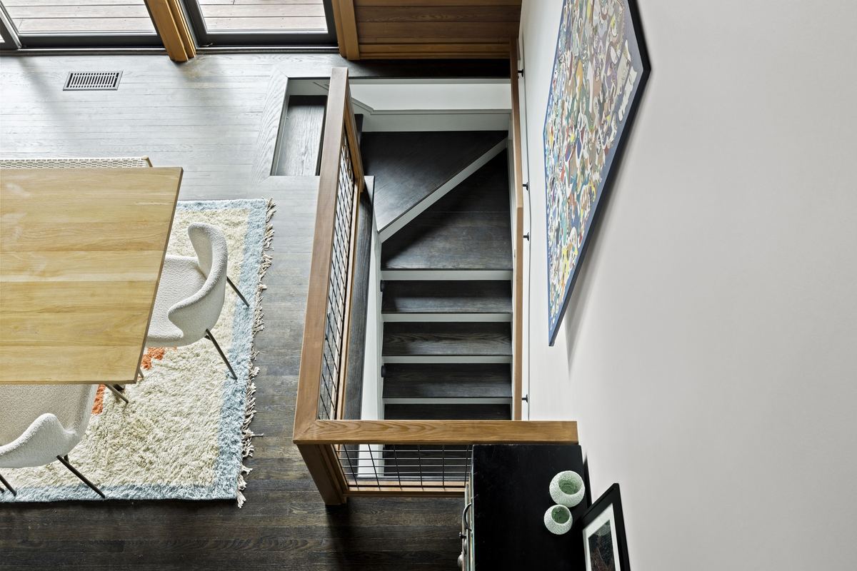 Looking down past the dining table to a dark stair and a tall painting