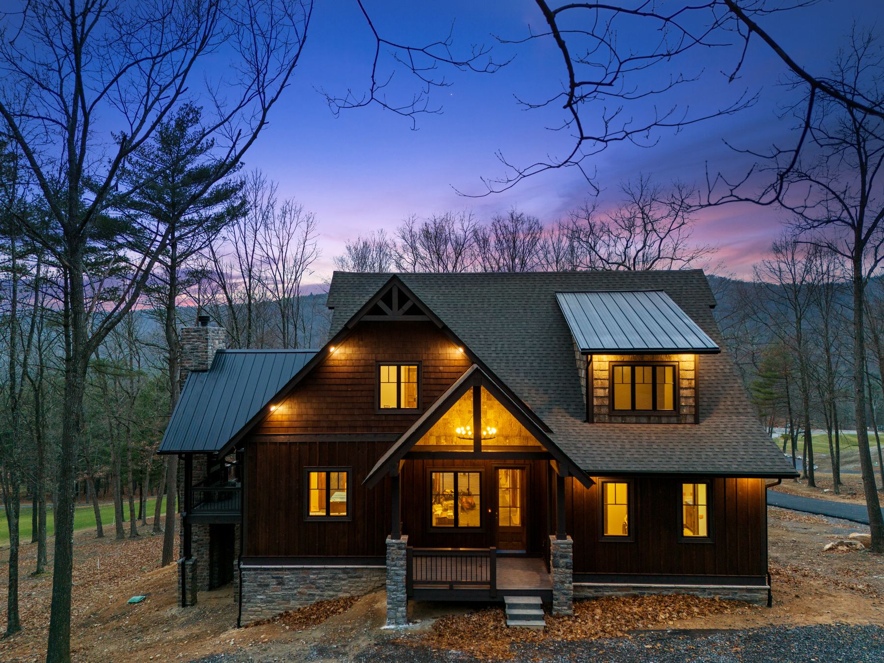 Mountain cabin lit from within at twilight in winter woods