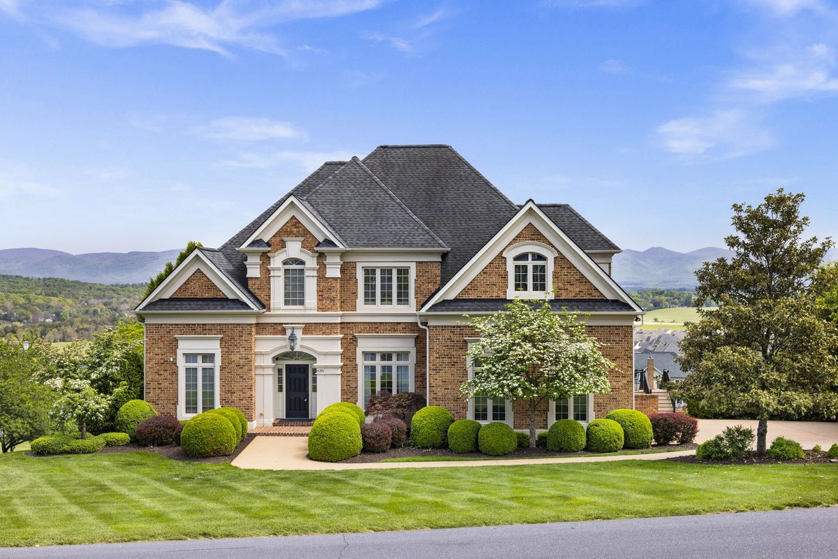 Brick estate home with a manicured lawn and mountain views