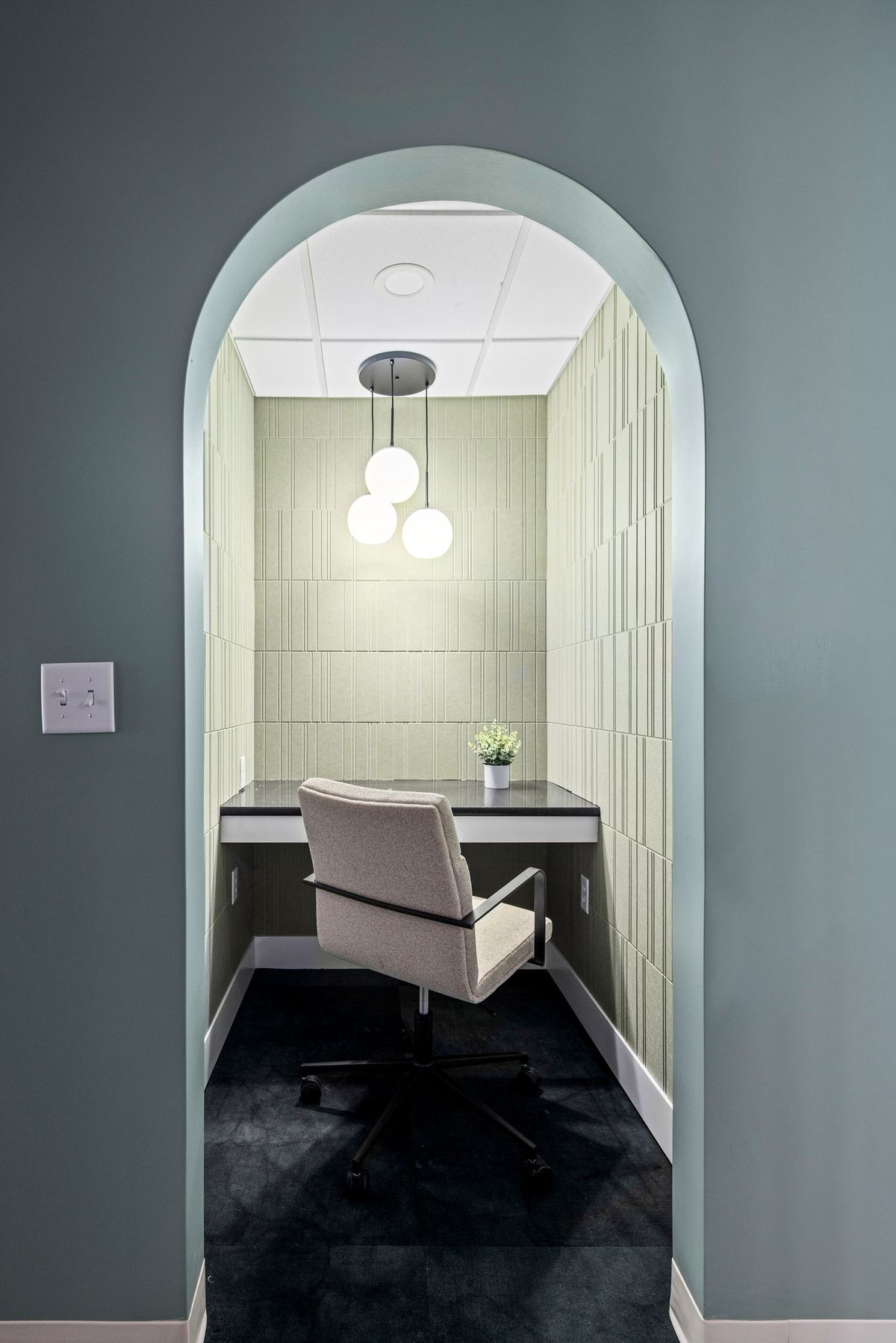 Arched doorway into a private office with a pendant light
