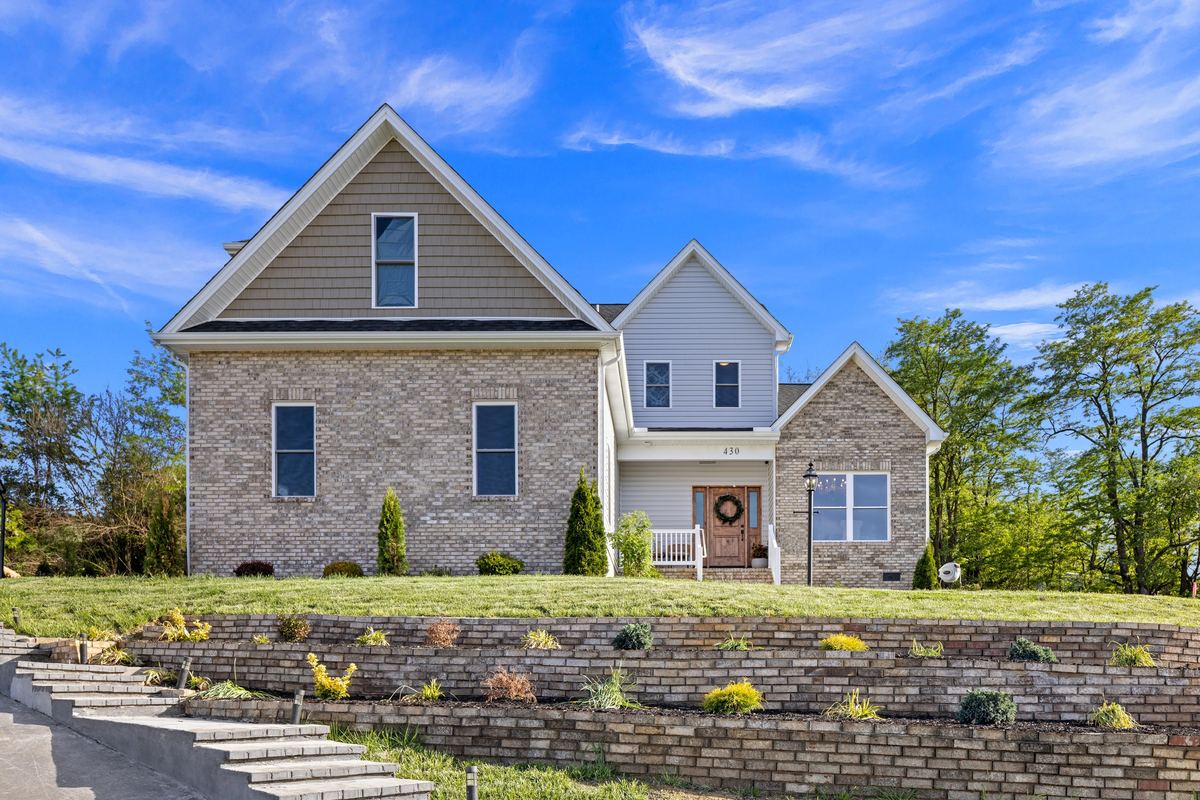 Brick and siding house above terraced stone walls, straight on, Penn Laird