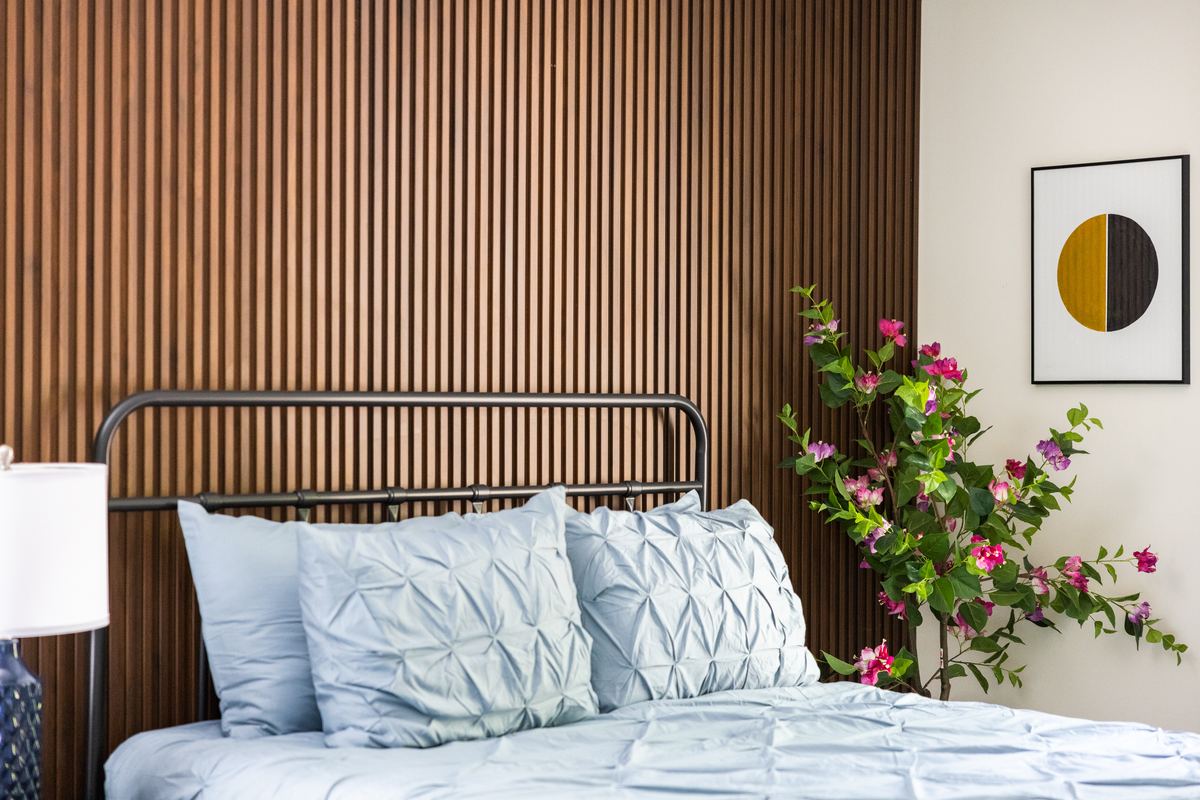 Bedroom with a fluted headboard wall, pale blue bedding and pink blossoms