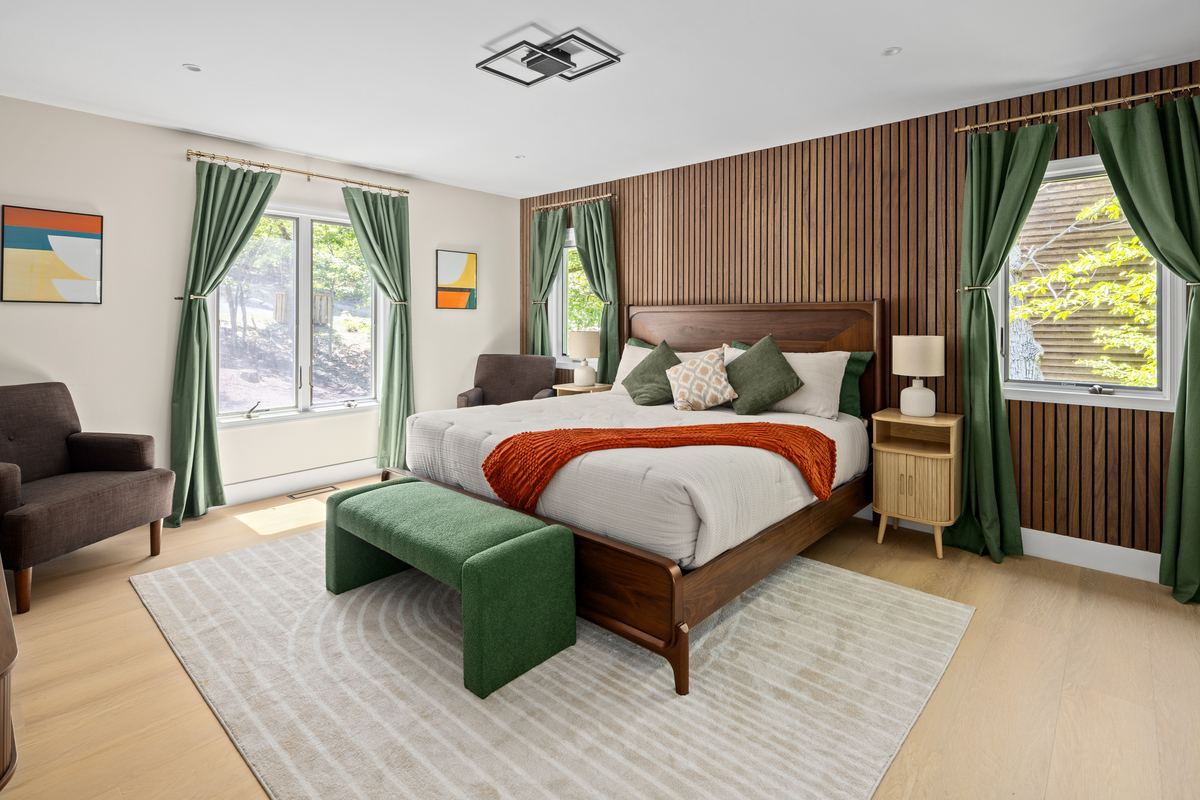 Bedroom with a fluted wood wall, green curtains and a mustard throw