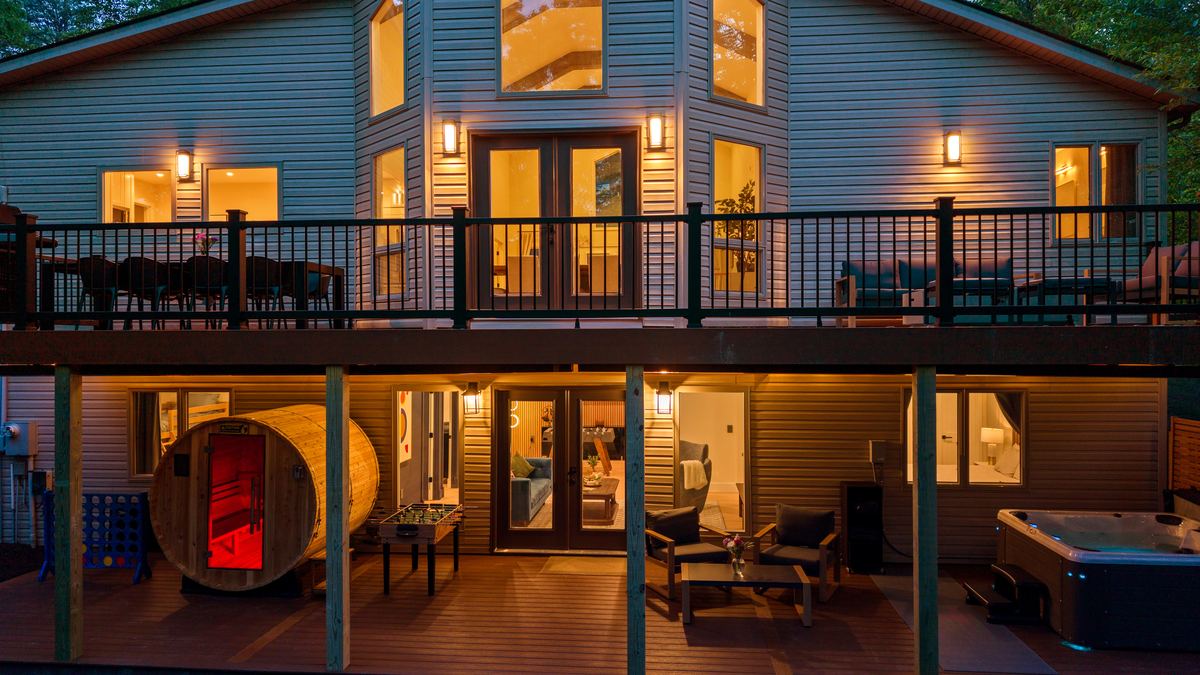 Two-level deck at dusk with sauna and hot tub