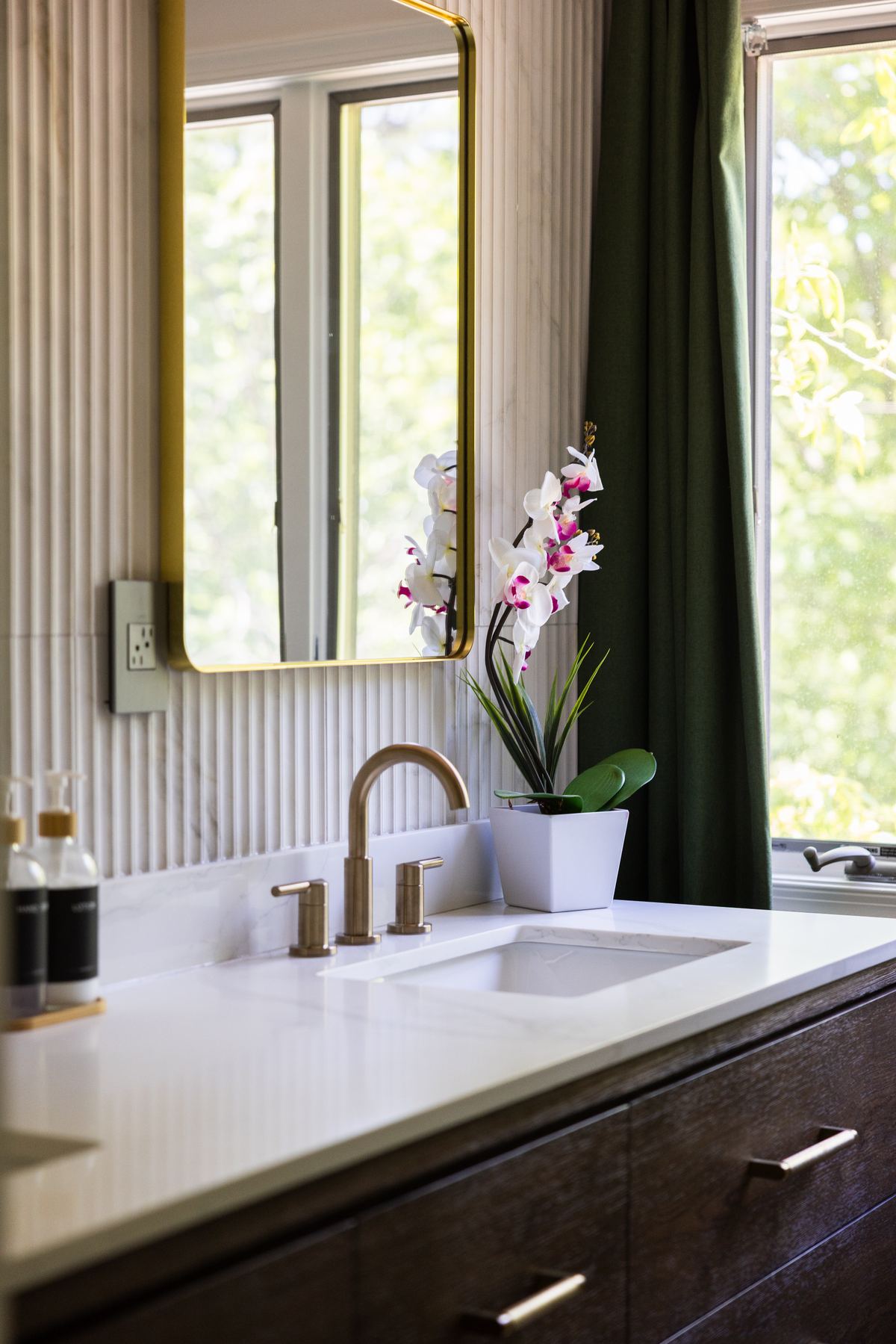 Bathroom vanity with brass fixtures and an orchid, Rainier Retreat