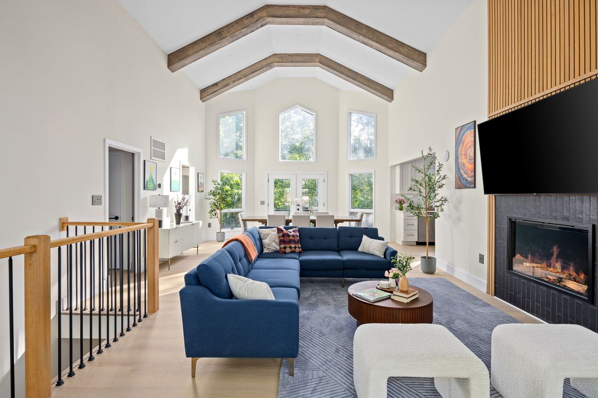 Vaulted living room with an exposed timber beam, linear fireplace and navy sectional