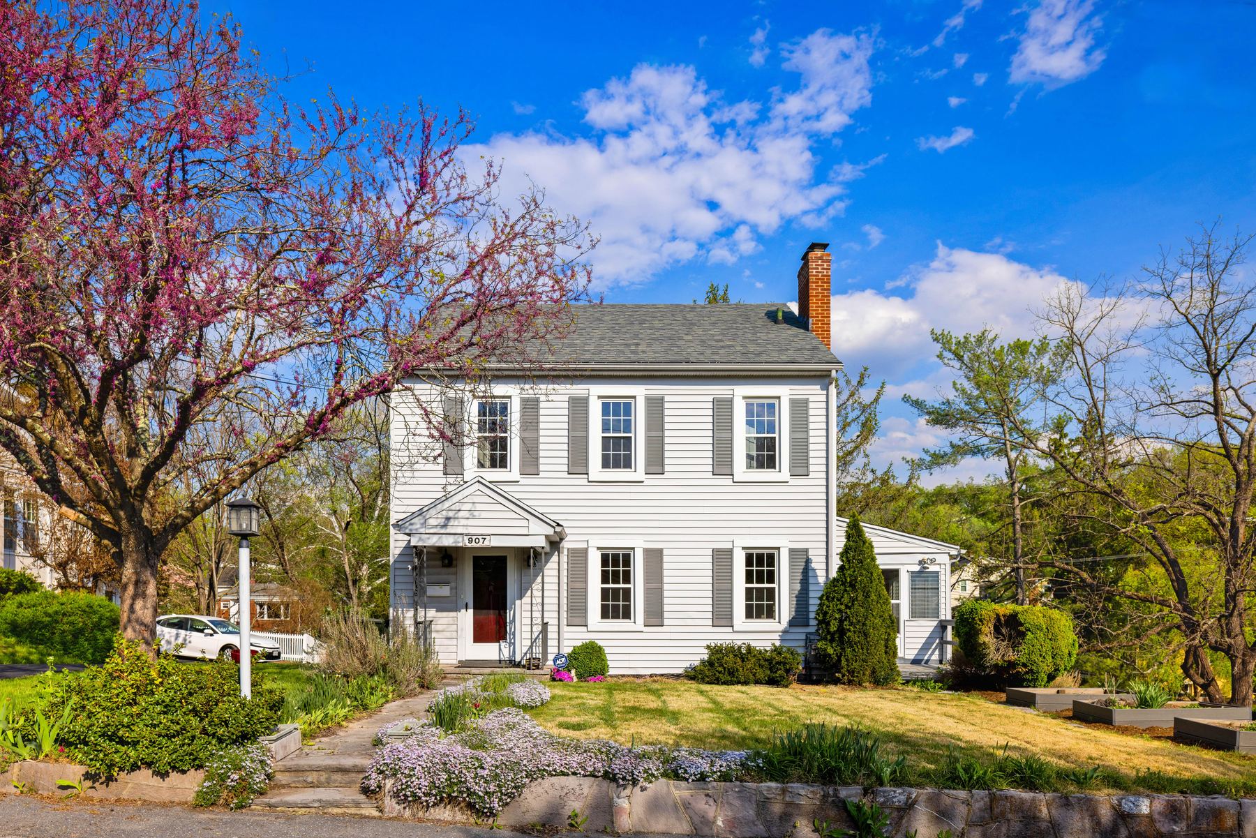 White home with a brick chimney under a blooming redbud in evening light, Staunton