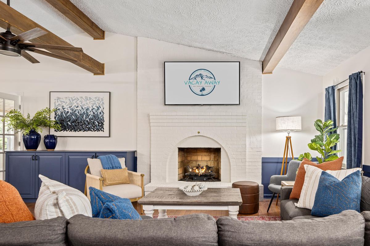 Great room with exposed beams and a fireplace in a river house rental