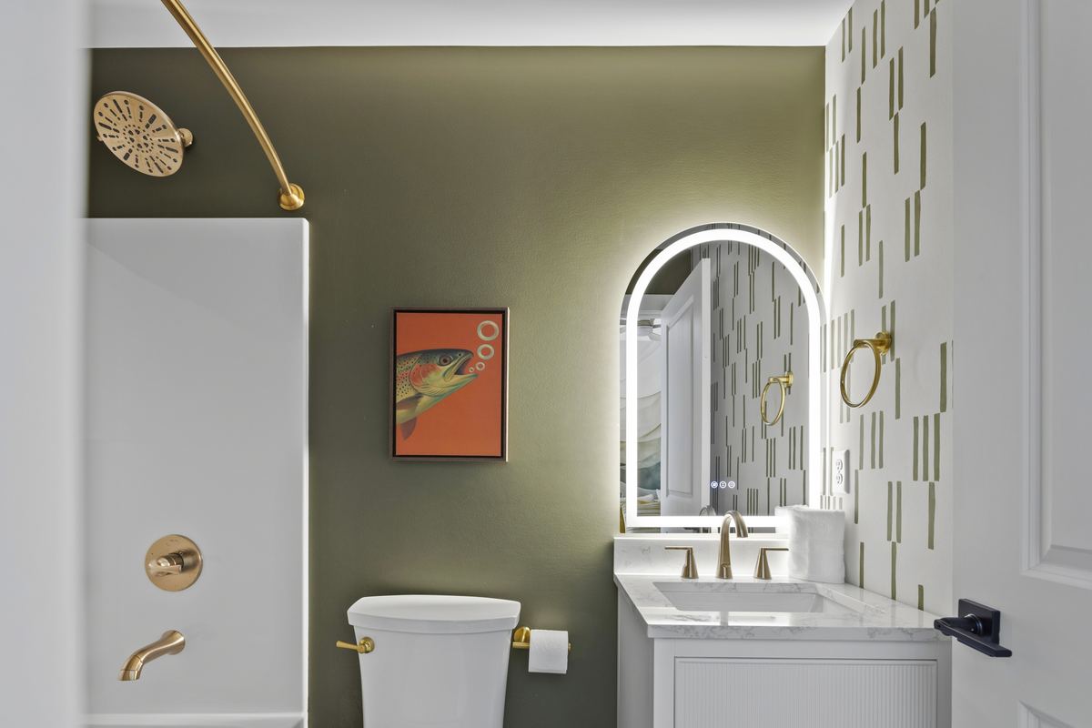Bathroom with green tile, arched mirrors and brass fixtures