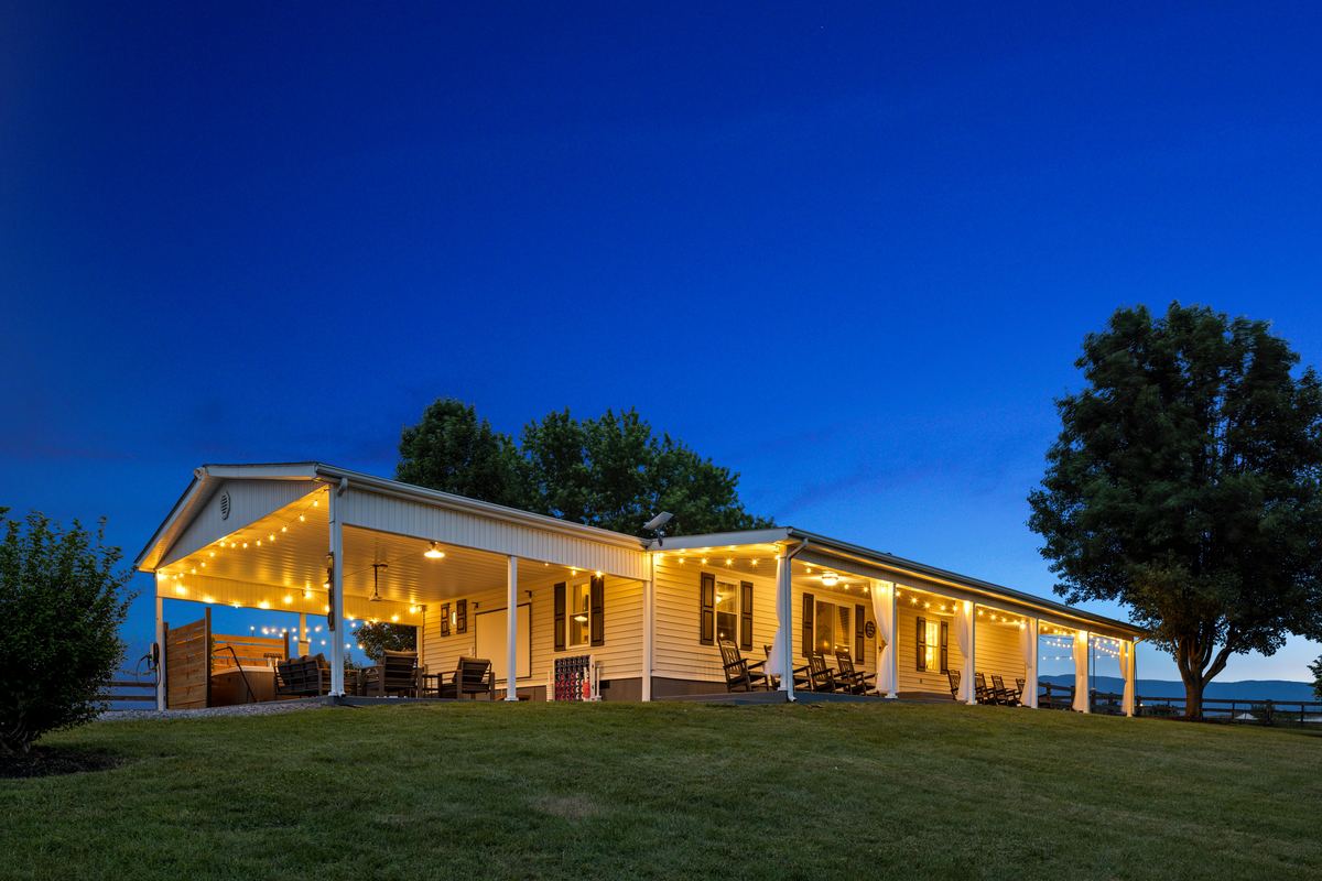 Ranch style vacation rental lit at twilight on an open lawn in Stanley, Virginia