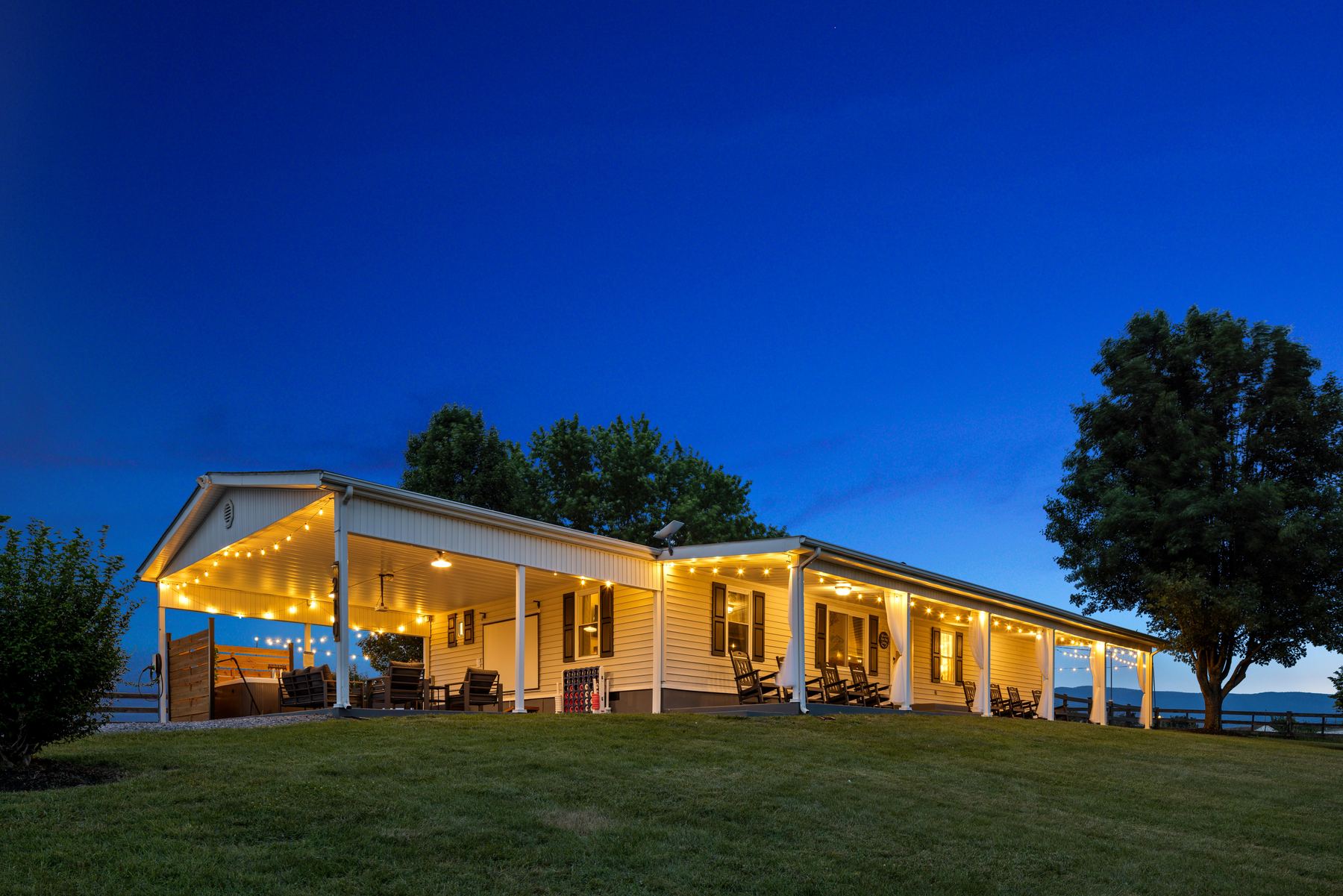 Ranch style vacation rental lit at twilight on an open lawn
