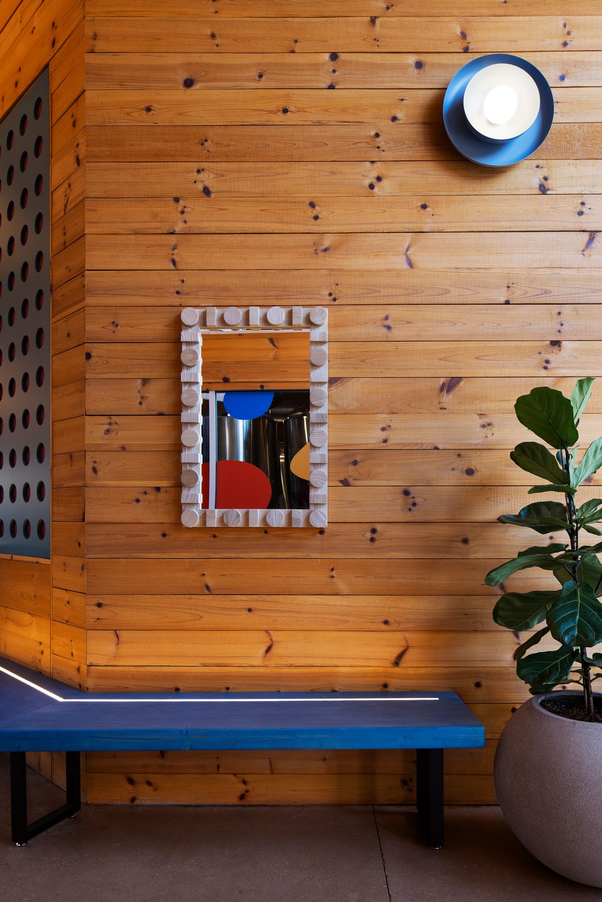 Blue bench and a tile-framed mirror on knotty pine