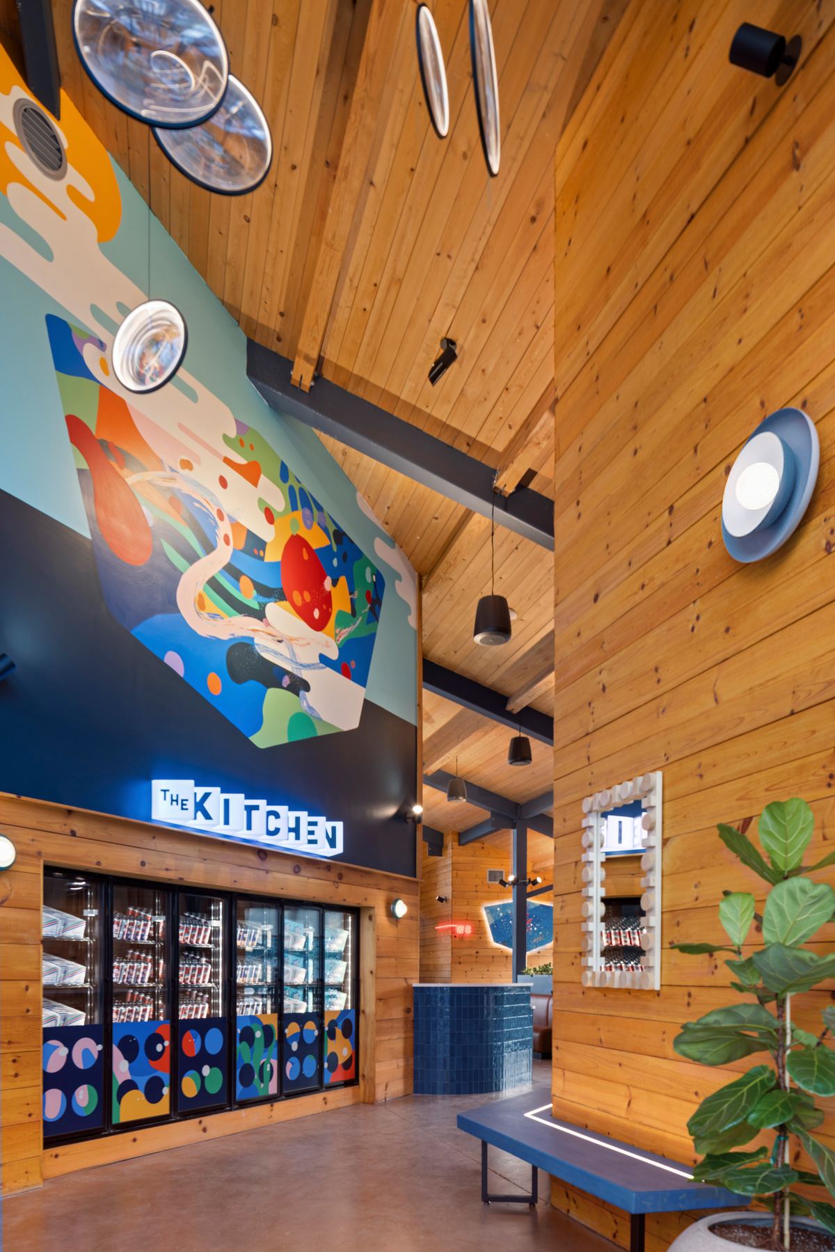 Kitchen pass under a bright mural with a fiddle leaf fig, Virginia Beer Co