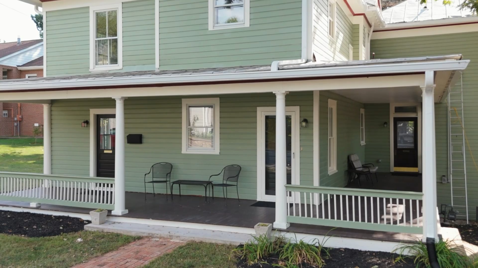 Frame from a listing film, a farmhouse porch pulling back to the full house